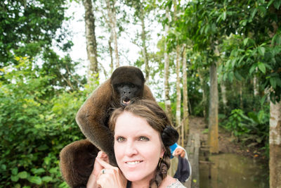 Portrait of woman with wooly monkey sitting on her shoulder at zoo