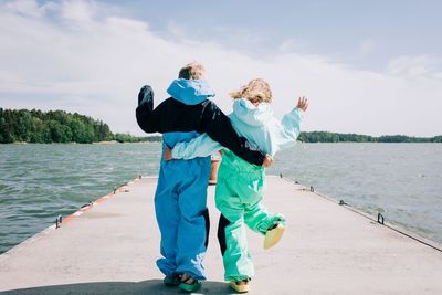 Rear view of friends standing by sea against sky