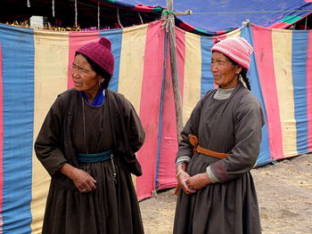 Mature women wearing traditional clothing standing by tent