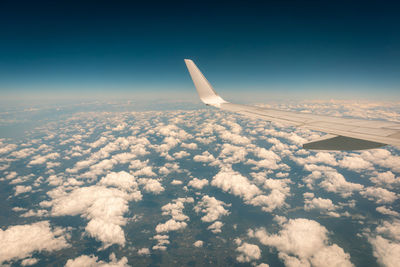 Airplane flying above the clouds at sunset.