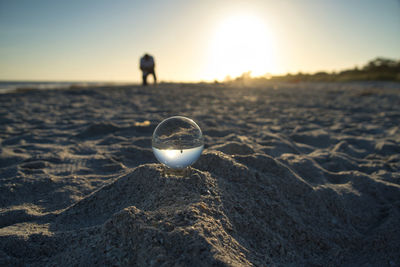 Close-up of crystal ball on beach during sunset