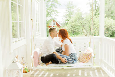 Couple sitting on swing in terrace