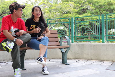 Full length of young couple sitting on seat