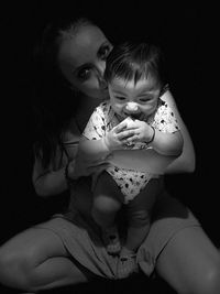 Low angle view of girl sitting against black background