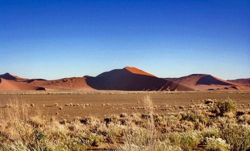 Scenic view of desert against clear blue sky