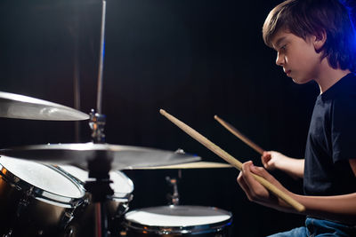 Side view of man playing drum