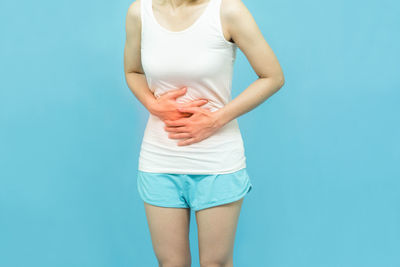 Midsection of woman standing against blue background