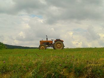 Scenic view of grassy field against cloudy sky
