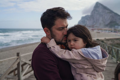 Rear view of man and holding daughter at sea shore