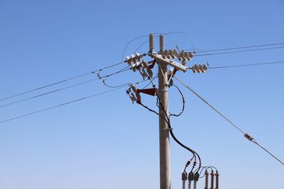 Low angle view of electricity pylon against clear sky