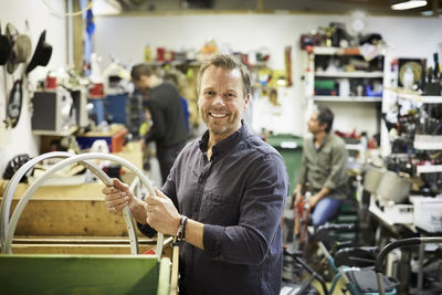 Portrait of smiling mature volunteer working against colleagues at workshop