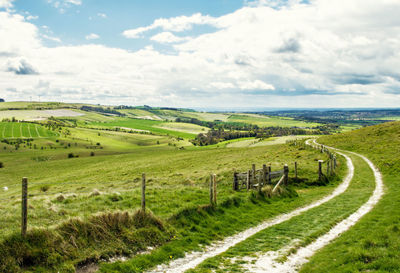 View of field against cloudy sky