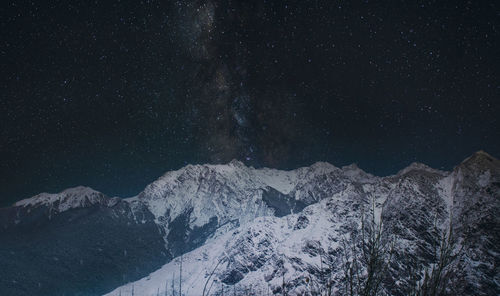 Scenic view of snowcapped mountain against sky at night