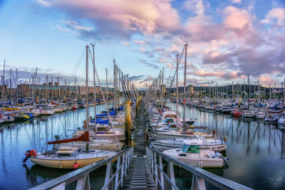 Boats moored at harbor against sky