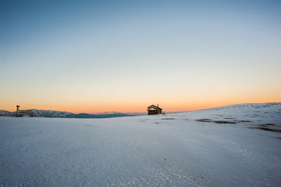 Scenic view of snow covered landscape against clear sky during sunset