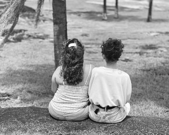 Rear view of woman sitting on field