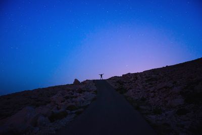 Low angle view of silhouette man standing on mountain against star field