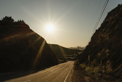 Road leading towards mountain against sky