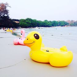 Yellow toy floating on swimming pool against sky