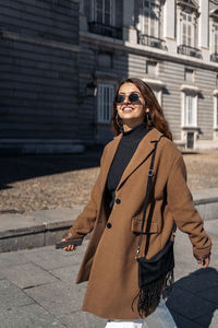 Young woman wearing sunglasses standing on street in city