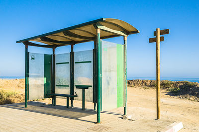 Lifeguard hut on beach against clear blue sky