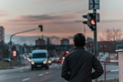 Rear view of man on street against sky at sunset