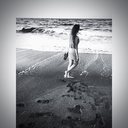 Full length of woman standing on beach against sky