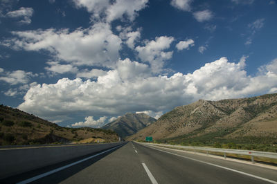 Road leading towards mountains against sky