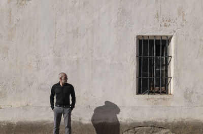 Portrait of adult man in suit standing against white wall with window