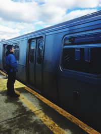 Side view of man standing by train at railroad station platform