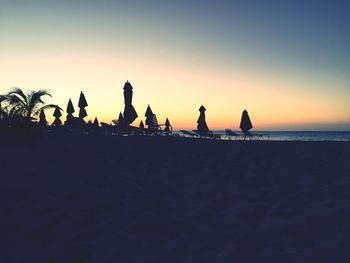Silhouette people on beach against clear sky during sunset