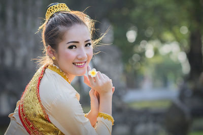 Smiling woman in traditional clothing standing outdoors