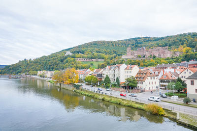 Buildings by river against sky in city