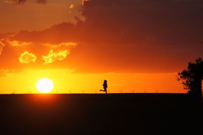 Silhouette man against orange sky