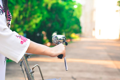 Cropped hand of woman holding bicycle handle outdoors