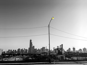 Cranes against buildings in city against clear sky
