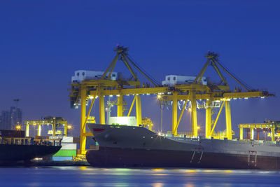 Illuminated pier at harbor against sky at night