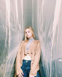 Beautiful young woman standing against wall