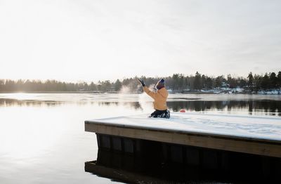 Boy throwing snow up in the air whilst playing outside by baltic sea