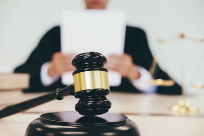 Close-up of gavel with judge sitting in background