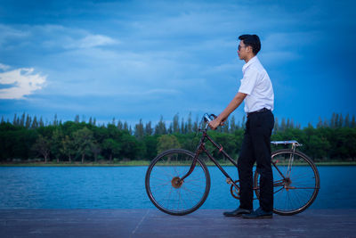 Side view of man riding bicycle against sky