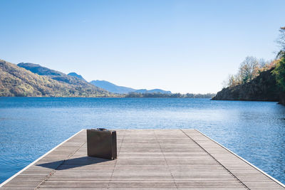 Swimming pool by lake against clear blue sky