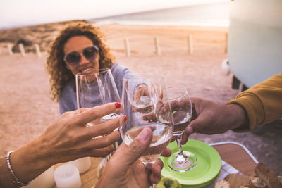 Friends toasting drinks while sitting at beach