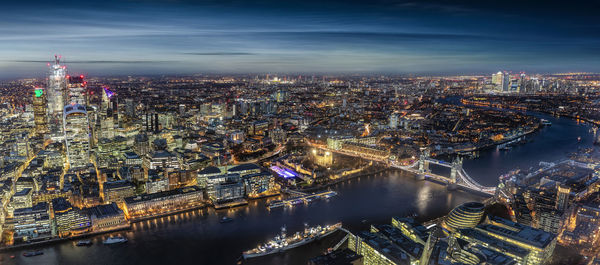 High angle view of illuminated buildings by river against sky