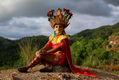 Portrait of man sitting against mountains against sky