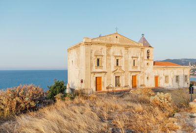 Building by sea against clear sky