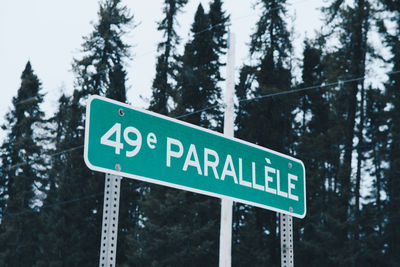 Low angle view of road sign against trees 