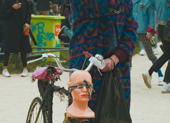 Midsection of person with mannequin standing by bicycle on street