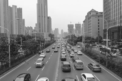 Traffic on road amidst buildings in city against sky