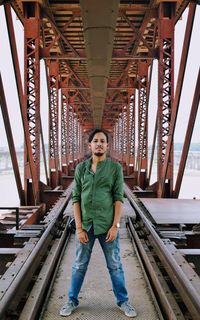 Full length portrait of young man standing on metal